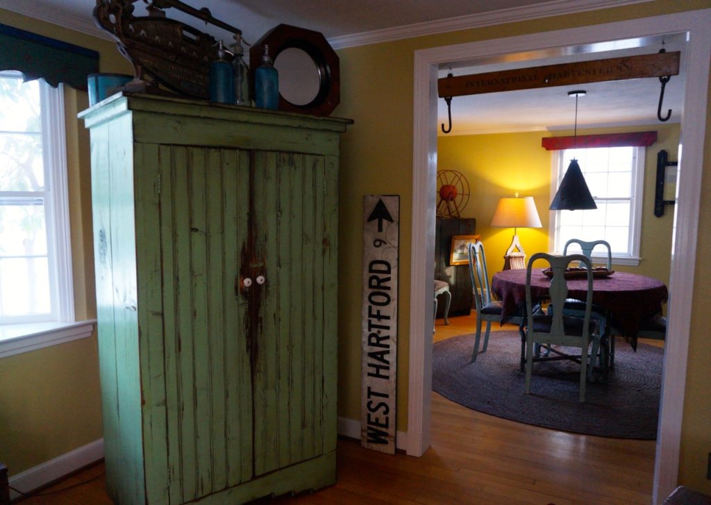 Next to the armoire that Jim Healy built to hide his TV is a sign that shows West Hartford at a distance of 9 miles. He has never been able to pinpoint where the sign might have once been. Photo credit: Ronni Newton