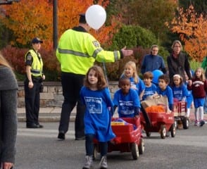 West Hartford Police Capt. Frank Fallon high-fives Morley students as he ensures their safety crossing Raymond Road. The Morley "Red Wagon Food Drive" delivers non-perishables to the West Hartford Food Pantry. Photo credit: Ronni Newton