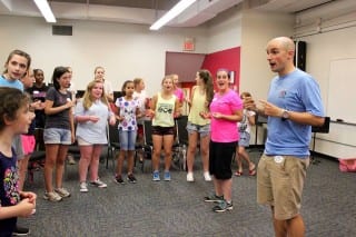 KO teachers David Baker ’04 and Rebecca Urrutia lead “the Downbeats,” Camp KO’s a cappella campers, in practice for their outdoor concert in front of Barnes & Noble in Blue Back Square on Thursday, July 16, 12:30-2 p.m. Submitted photo