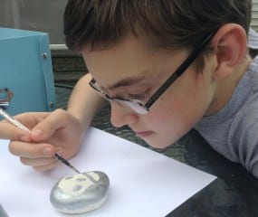 Cameron Hurley carefully paints a rock. Photo credit: Julie Phillipps