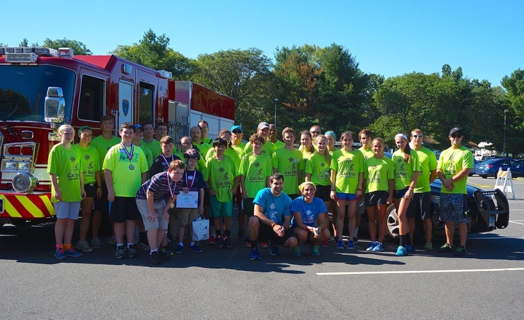 Campers and volunteers from session one pose in front of a West Hartford fire engine and police cruisure following the iCan Bike camp graduation ceremony Friday morning. Photo credit: Ronni Newton
