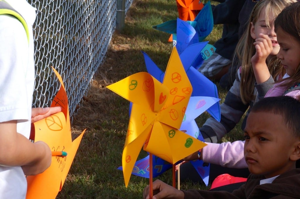 Second graders at Charter Oak International Academy plant their pinwheels along the fence. Photo credit: Ronni Newton
