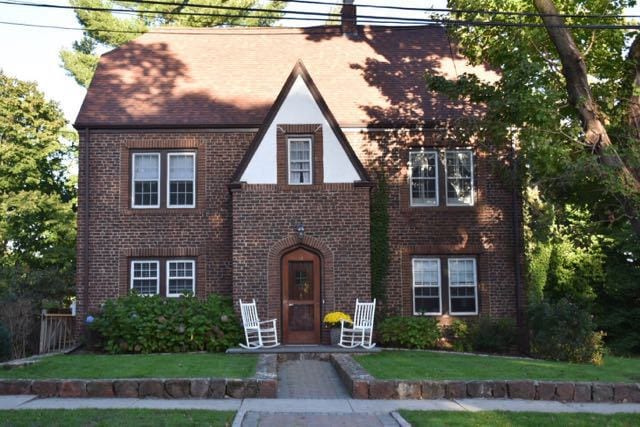 Charming brick Tudor with inviting rockers out front. Photo credit: Deb Cohen