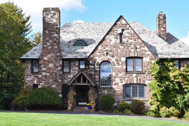 Tudor Revival home with unusual stonework on the facade and a slate roof. Photo credit: Deb Cohen