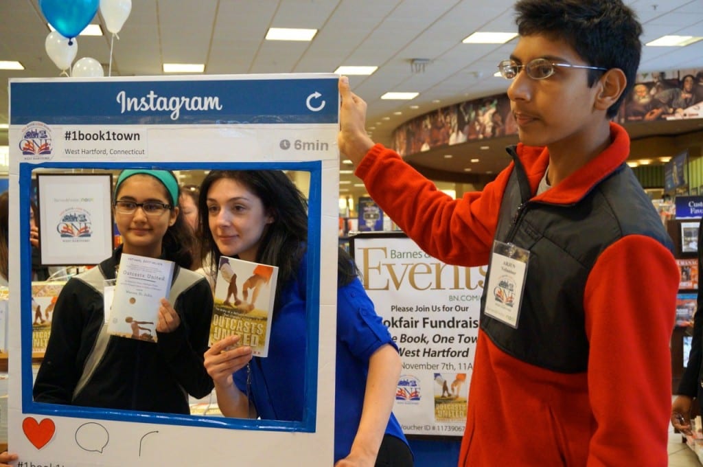 West Hartford student volunteers (from left) Faizah Kiran, Milena Danzi, and Arjun Jagjivan pose with the 'One Book, One Town' Instagram frame. Photo credit: Ronni Newton