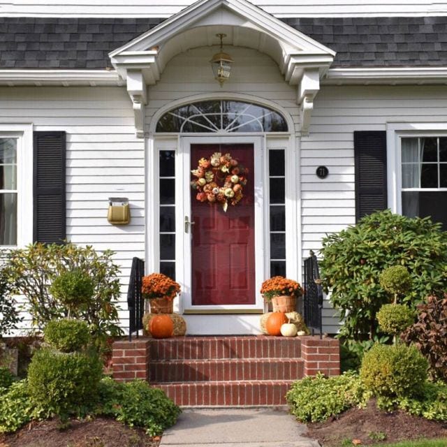 An elaborate fall wreath, mums in bushel baskets and a collection of pumpkins look great with this burgundy door. Photo credit: Deb Cohen
