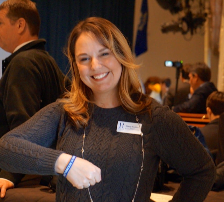 Director of Marketing and Communications Stacy Routhier shows off a special bracelet that everyone wore the 80th anniversary assembly. Photo credit: Ronni Newton