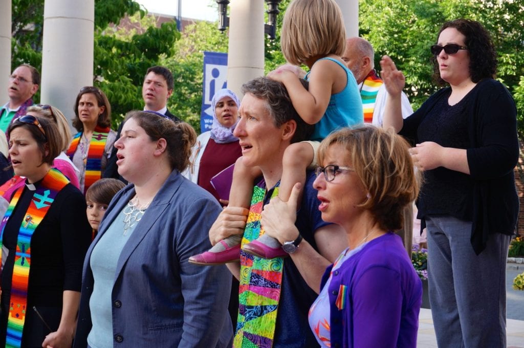 Shari Cantor (right) and area clergy hold hands and sing 'We Shall Overcome' at Wednesday night's vigil. Photo credit: Ronni Newton