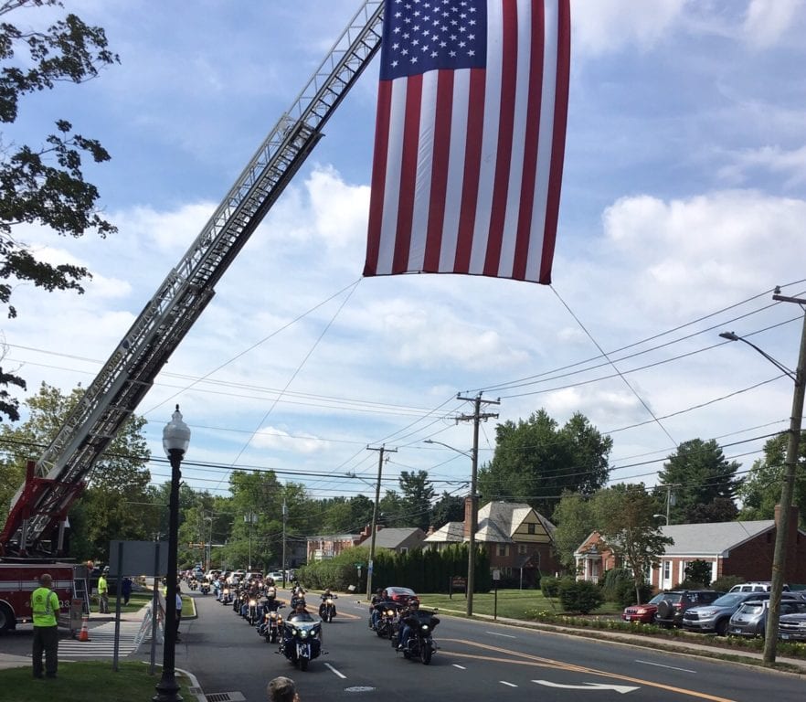 The Wall of Remembrance is escorted up South Main Street by CT Friends of Veterans, and passes under a flag arch created by the West Hartford Fire Department. Photo courtesy of Paul Shea
