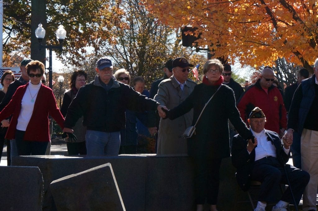 The crowd joins gathered at the Veterans Memorial joins hands for a moment of silence. Veterans Day, West Hartford, Nov. 11, 2016. Photo credit: Ronni Newton