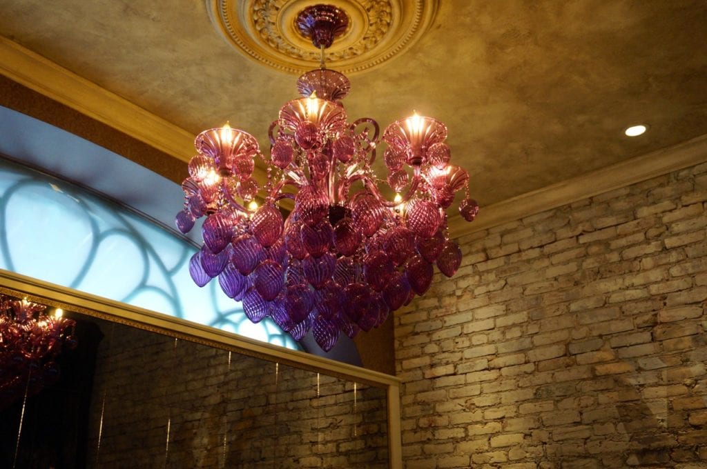 This purple chandelier gives a glow to the plush seating in the bar area at Noble & Co. Photo credit: Ronni Newton