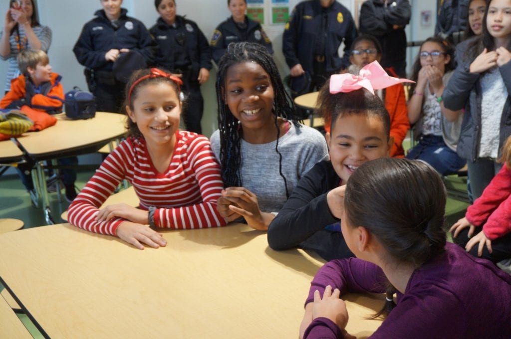Charter Oak International Academy fifth-grader Faith Brown (with pink bow) shares a laugh with her friends during lunch period Thursday, before realizing that she is about to be the center of attention. Photo credit: Ronni Newton