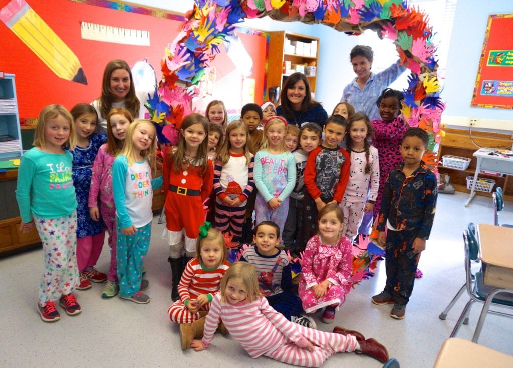 Pajama-clad Bugbee first graders with the peace wreath. Adults include (from left) Curriculum Specialist Katie Feldman, Principal Kelly Brouse, and teaching assistant Ellen Eikenhorst. Photo credit: Ronni Newton