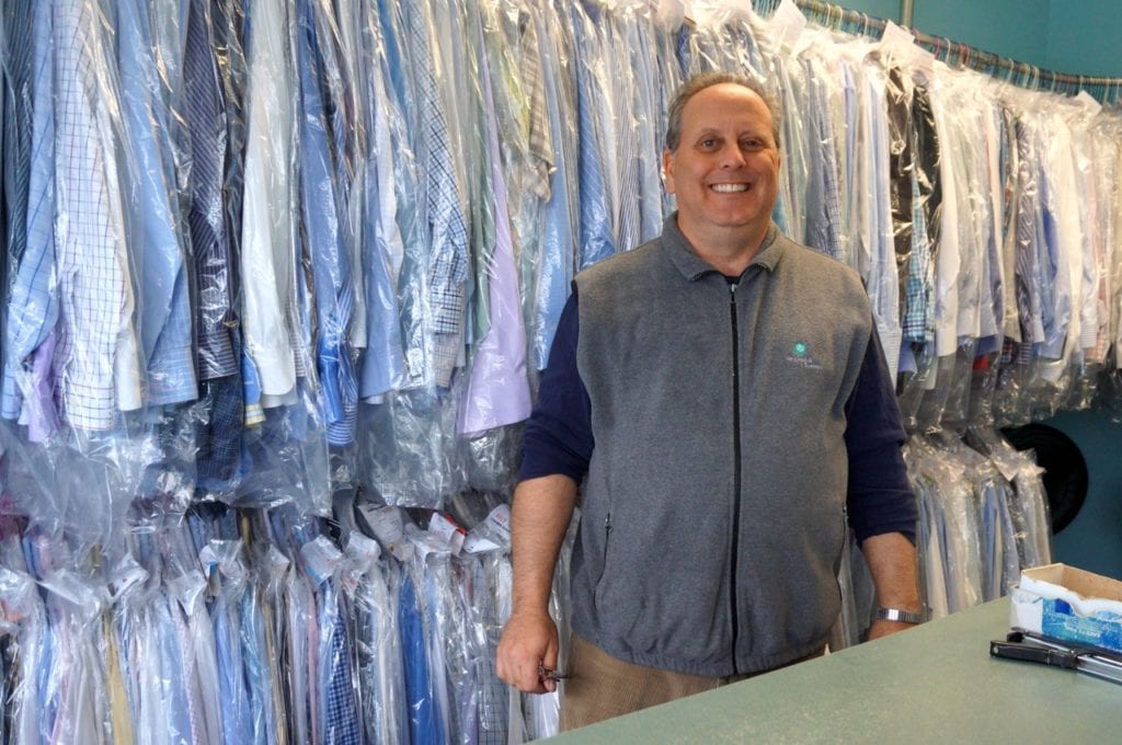 Sedgwick Cleaners owner Dana Gordon stands at the counter in front of shirts that will need to be picked up before the business closes for good on Dec. 31, 2016. Photo credit: Ronni Newton