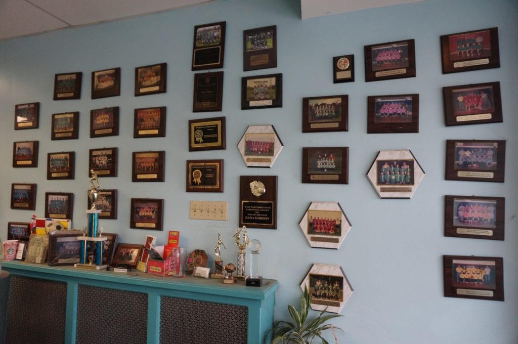 A wall of plaques and photos from the youth sports teams that Sedgwick Cleaners has sponsored over the years. Photo credit: Ronni Newton