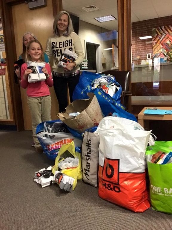 Braeburn first grade teacher Marta Weidl with Hannah (front) and Olivia Bywater and some of the 750 pairs of socks that were collected. Photo courtesy of Bryan Bywater