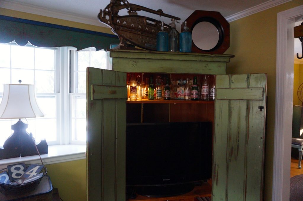 Healy built the armoire to hide his TV (and store some of his glass bottles). It's made from new wood, that he distressed. Photo credit: Ronni Newton