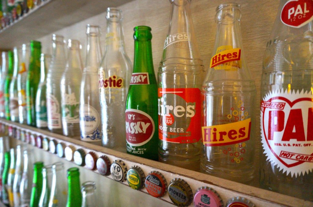 More bottles on display in a shelf appropriately adorned with vintage bottle caps. Photo credit: Ronni Newton