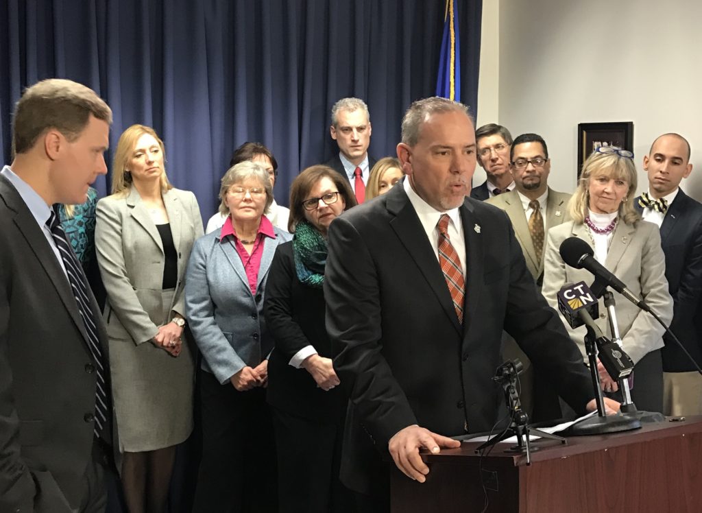 State Rep. Derek Slap of West Hartford (in rear, fifth from left) listens while House Speaker Joe Aresimowicz (at podium) speaks about a bill they are sponsoring with other House members to support small businesses. Submitted photo