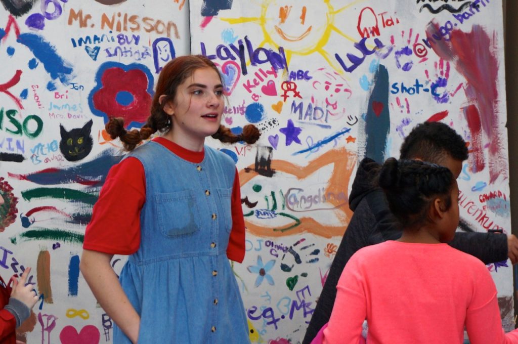 Pippi Longstocking (Maddie Schwartz), with crazy braids and mismatched socks, invites students to paint on her wall. Conard Fictional Characters Day. Photo credit: Ronni Newton