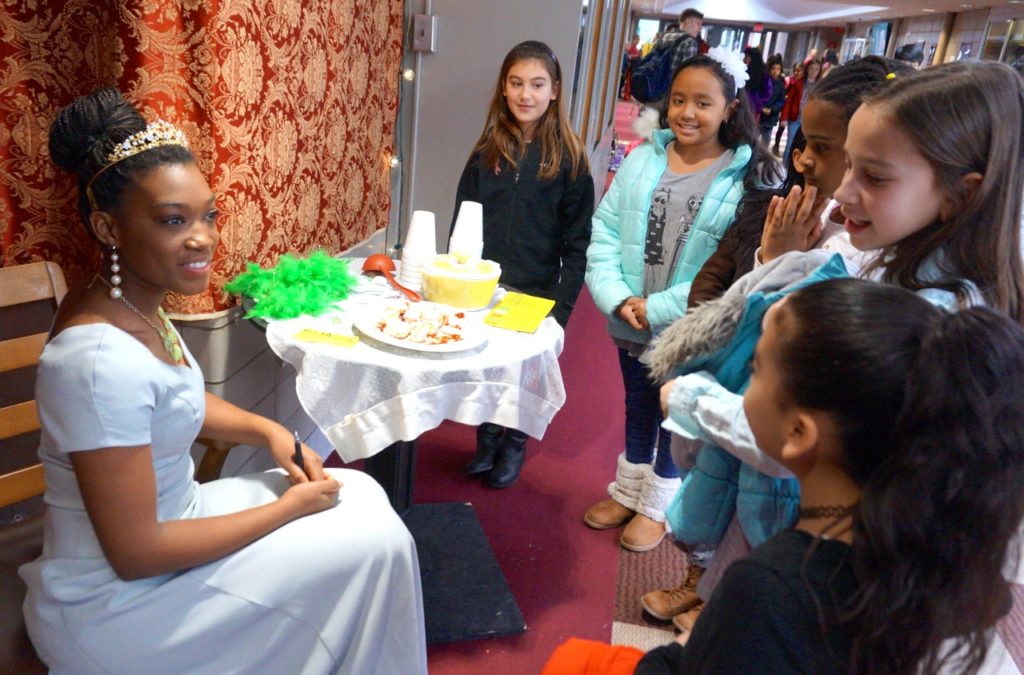 Princess Tiana from The Princess and the Frog (Casey Wilson), with a plate of beignets in front of her, speaks with Charter Oak students. Conard Fictional Characters Day. Photo credit: Ronni Newton