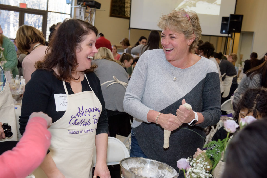 From left: Barbara Dell and Myra Emrick joyfully braid their challas. Submitted photo (credit: Nick Caito Photography)